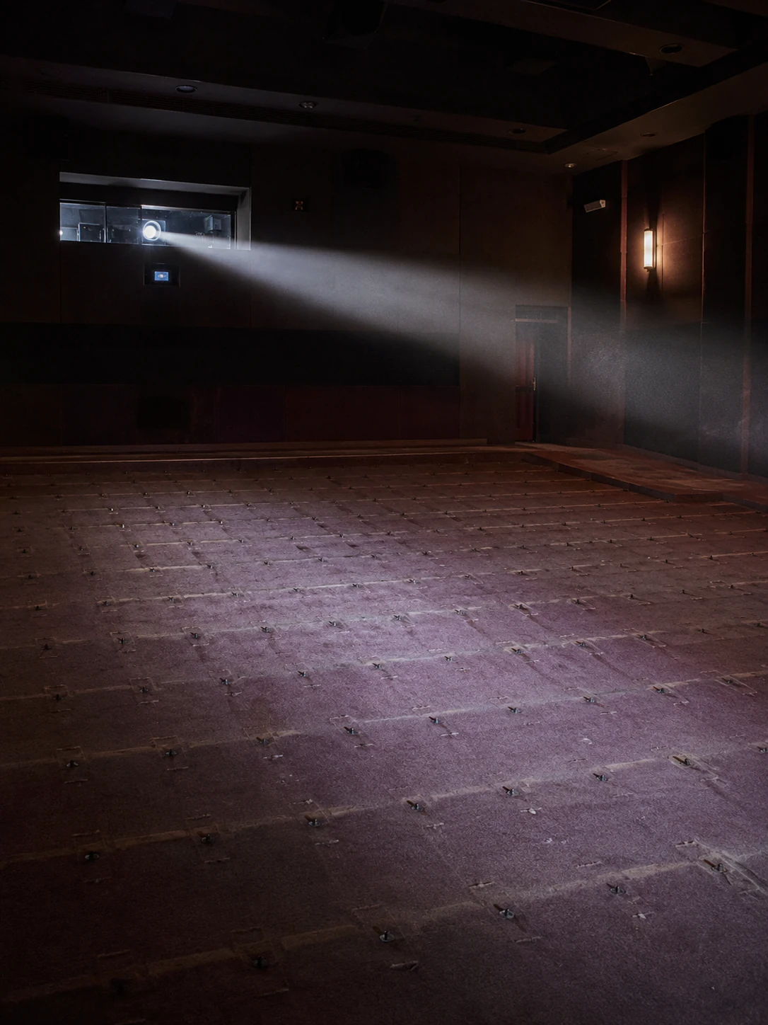AI-generated dark space with a single horizontal projection beam above repeated impressions in the floor.
